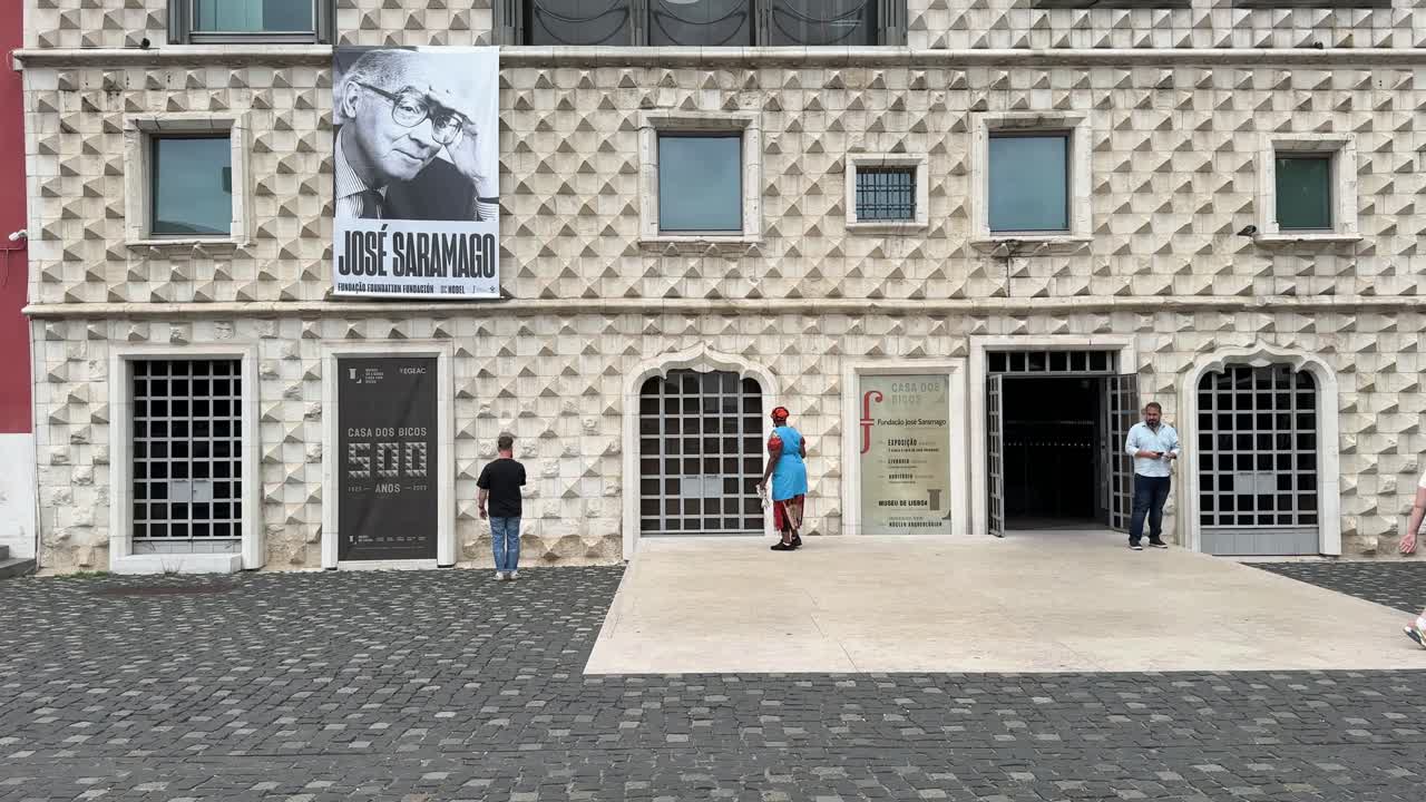 People walk outside the famous Casa dos Bicos in Lisbon, Portugal.