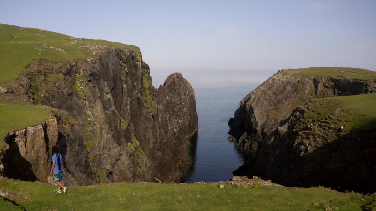 Man strides to the cliff's edge, embracing Inisbofin's landscape