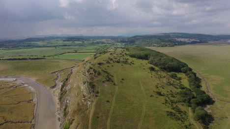 Aerial-landscape-of-a-hill-formation-on-the-coast-line-at-low-tide,-on-a-bright-day