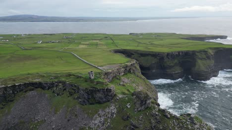 una toma aérea de una torre de vigilancia en ruinas con vistas a los acantilados de moher