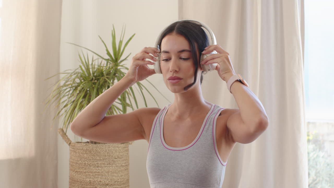 Woman meditating at home wearing headphones, focusing on breathing exercises