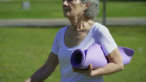 Seitenansicht-Einer-Frau,-Die-Im-Park-Spaziert-Und-Eine-Yogamatte-In-Der-Hand-Hält