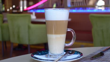 a tall glass of latte with whipped cream in a cafe