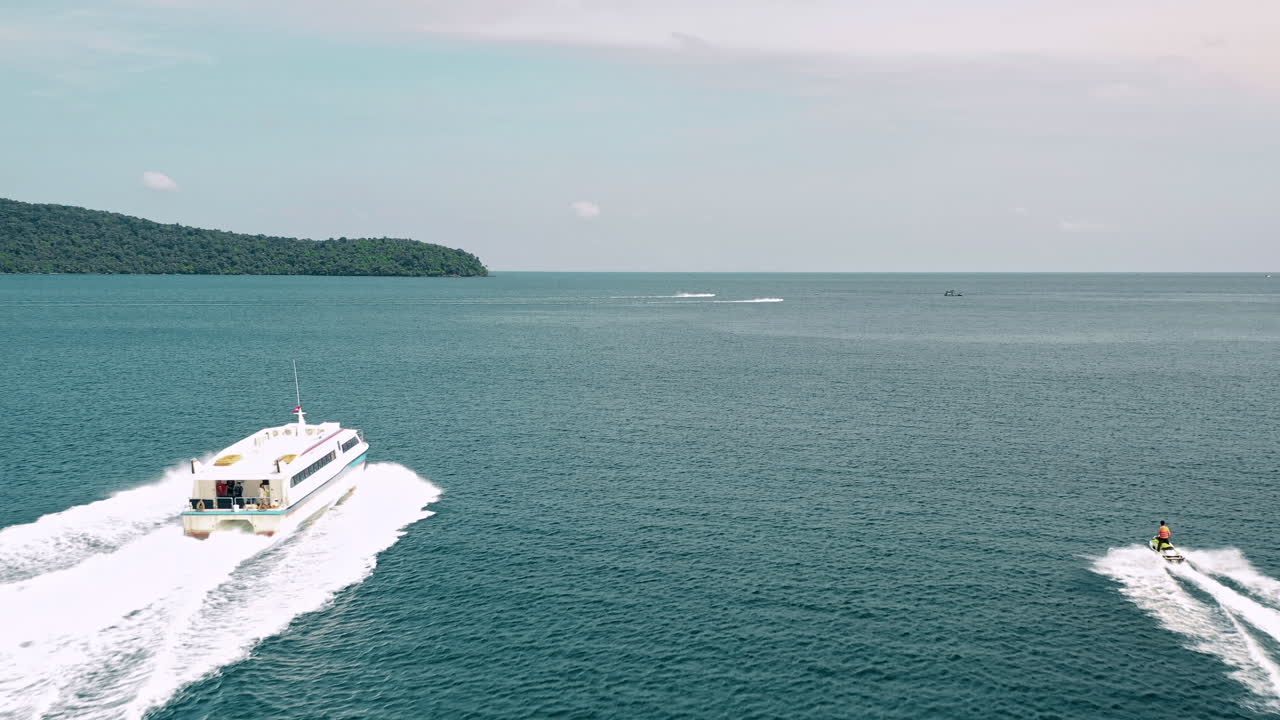 Following a large tour boat and jet ski racing across the bay of Rong Samloem, Cambodia, aerial