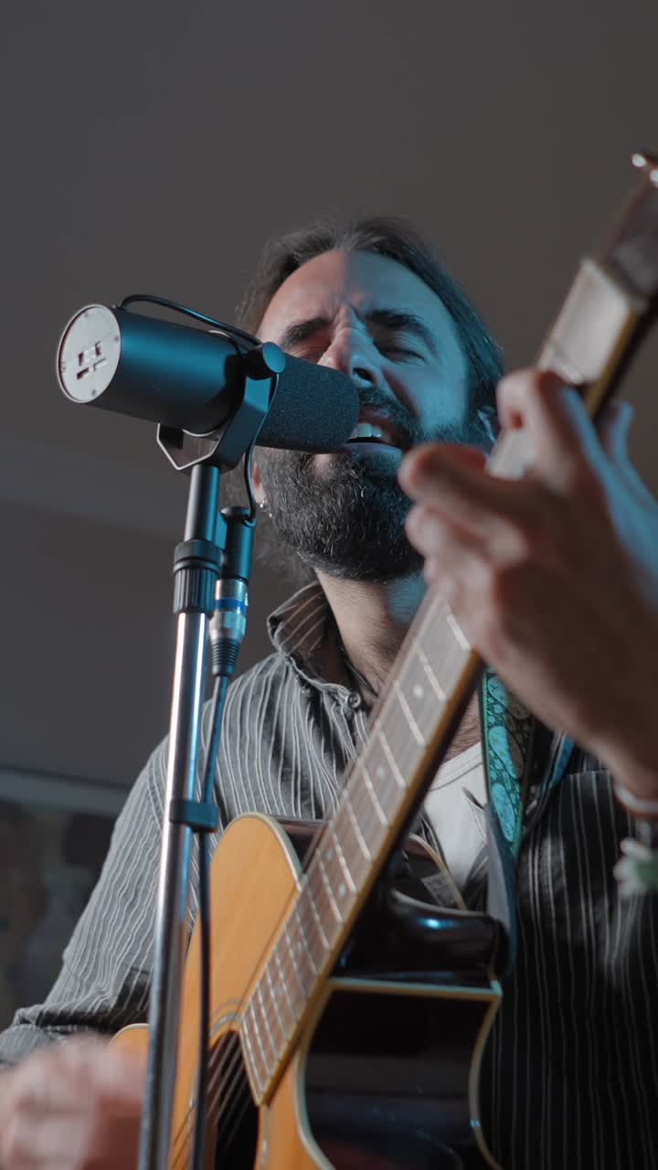 Uomo che suona la chitarra acustica e canta in un microfono