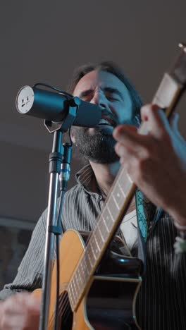 man playing acoustic guitar and singing into a microphone