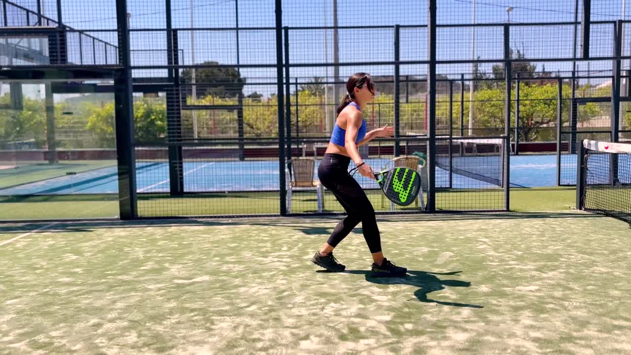 Giovane coppia di sportivi (donna e uomo) che gioca a padel tennis al rallentatore. Colpendo la palla da padel in slow motion su un campo da padel