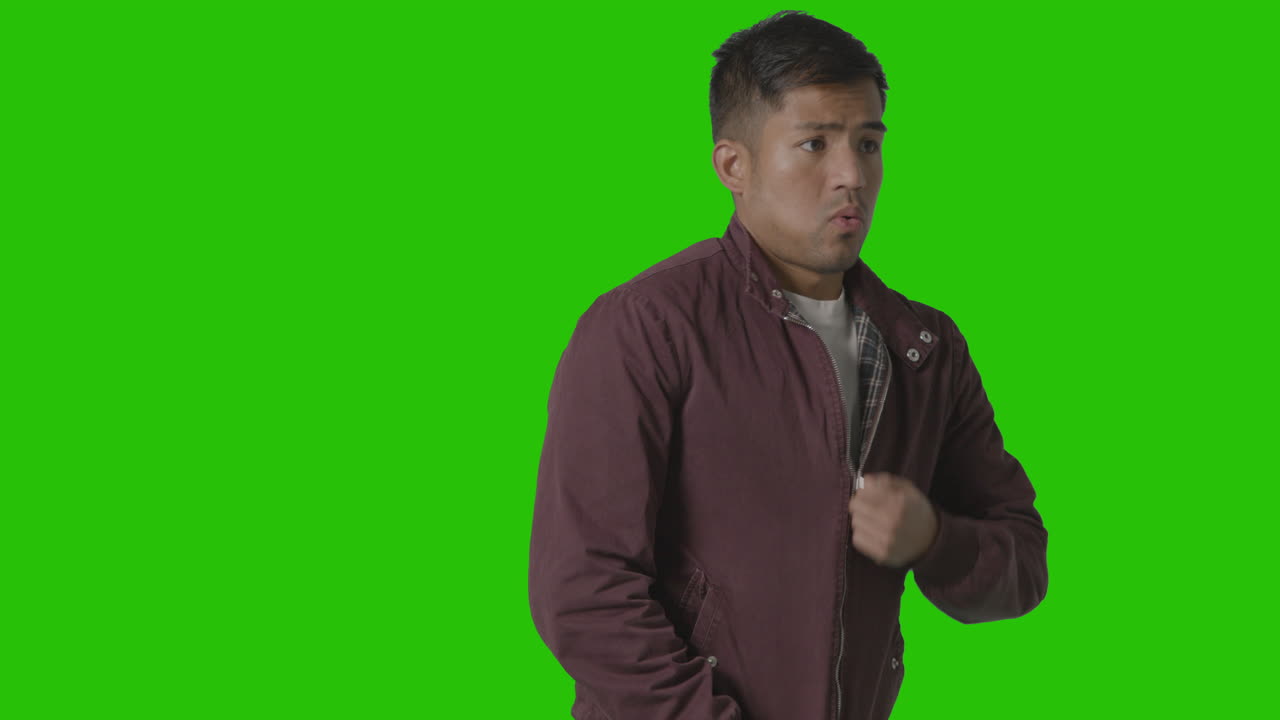 retrato de un joven vestido de forma informal y temblando de frío haciendo un abrigo contra la pantalla verde