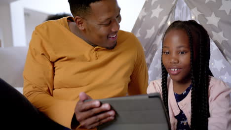 Happy-african-american-father-with-daughter-using-tablet-at-teepee,-slow-motion