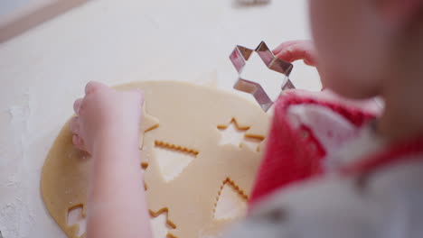 close up of a boy cutting out christmas cookies in dough