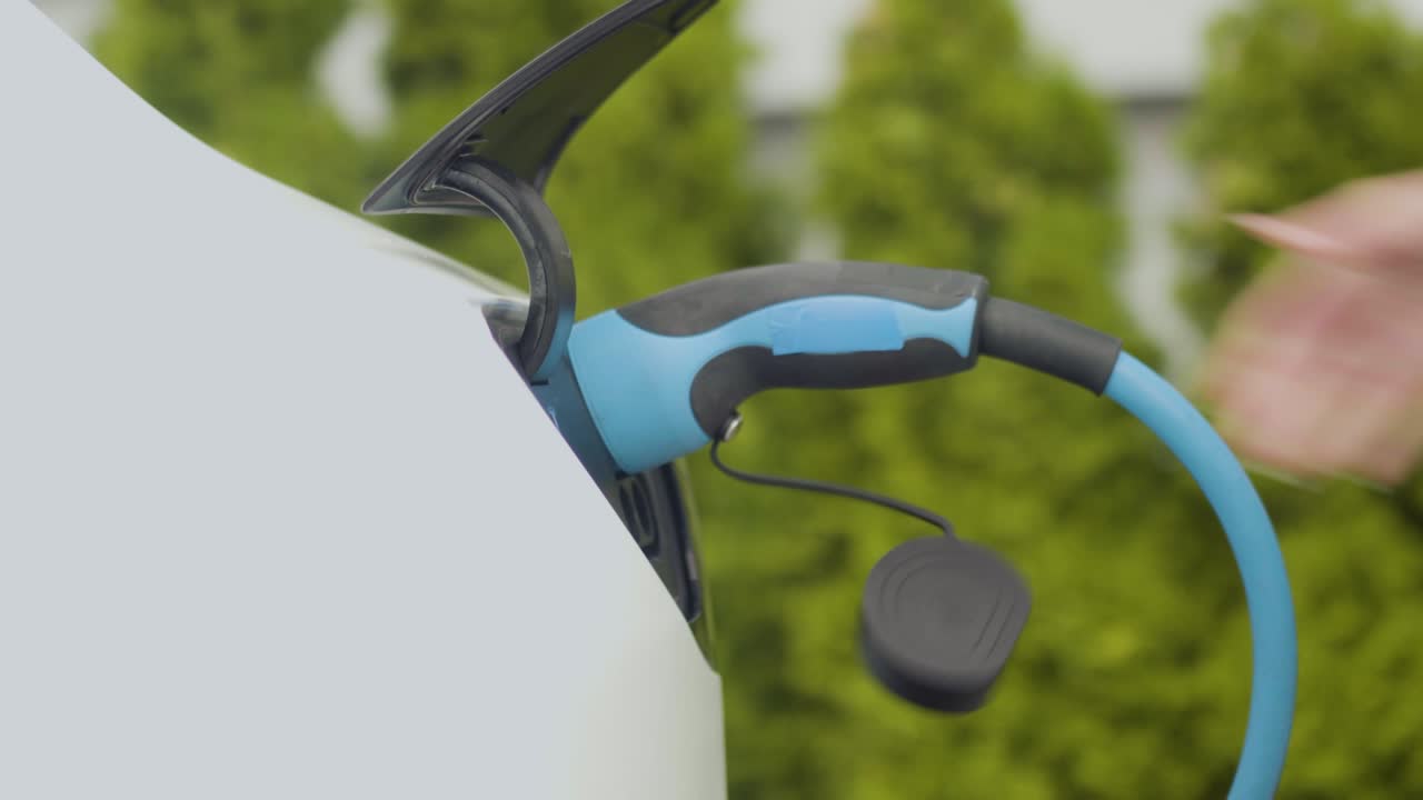 전기 자동차의 충전 소켓에 전원 케이블을 는 여성 손