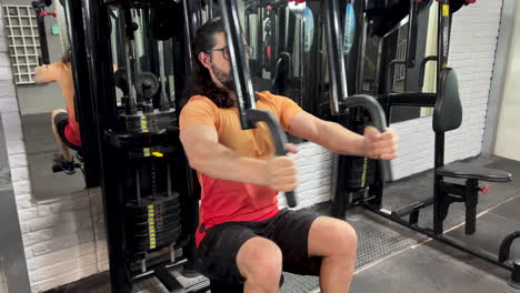 latin man with beard and long hair performing crucifixion exercise on machine