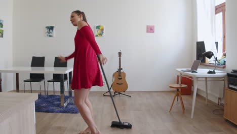 a young woman sweeps the floor while dancing