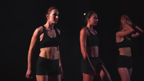 tres chicas vestidas de negro están en las plataformas de salida para comenzar la carrera en la competencia.