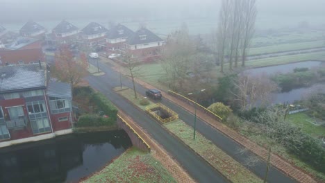 Aerial-of-car-driving-through-a-mist-covered-suburban-neighborhood