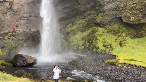 european female tourist walking towards kvernufoss awesome waterfall in iceland