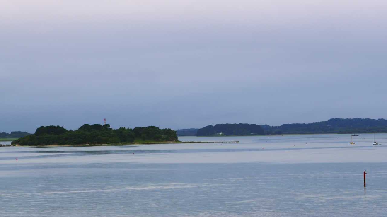 Early Morning View from Poole Harbour with Small Island with Dense Forests and Surrounding Calm English Channel Sea and Moored Sailing Boats 4K