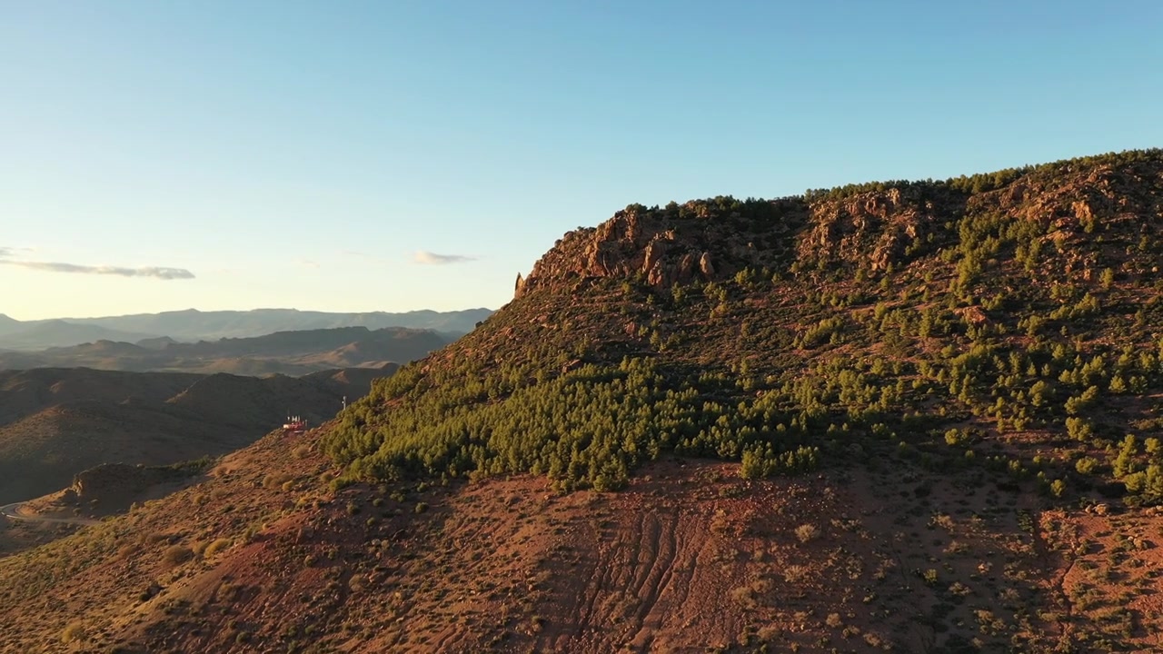 Riprese aeree cinematografiche con drone di un aspro crinale roccioso di alta montagna illuminato dalla calda luce dorata del tramonto nel Medio Atlante, Marocco, ideale per progetti di viaggi d'avventura e documentari sulla natura.