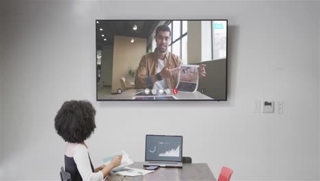 mujer de negocios afroamericana en una llamada de video con un colega afroamericano en la pantalla de televisión