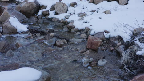 Water-runs-down-a-small-creek-with-snow-on-the-side