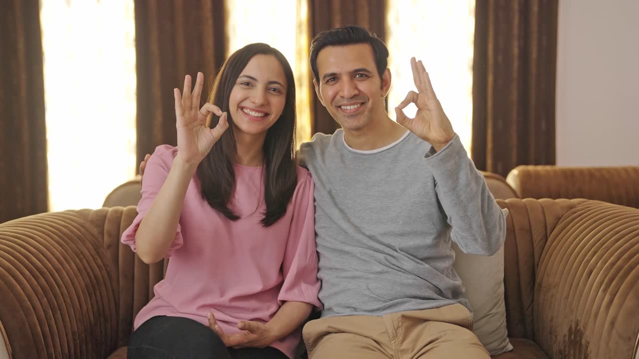 una feliz pareja india mostrando una señal de acuerdo a la cámara