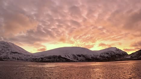 beautiful sunset in orange cloudy sky over rolvsøya island. timelapse.