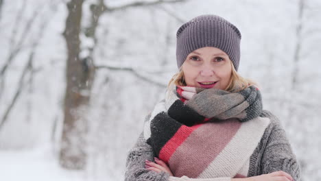 a woman in a warm sweater and a bright scarf stands in a snow park