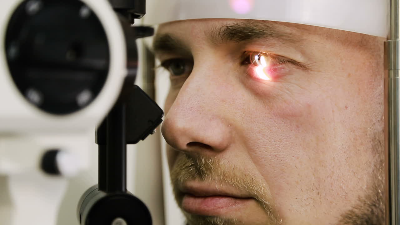 Man having eye test. Female optometrist examining mans eyes through slit lamp in clinic