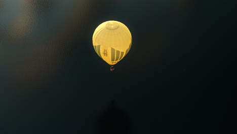 yellow hot air balloon flying low over water