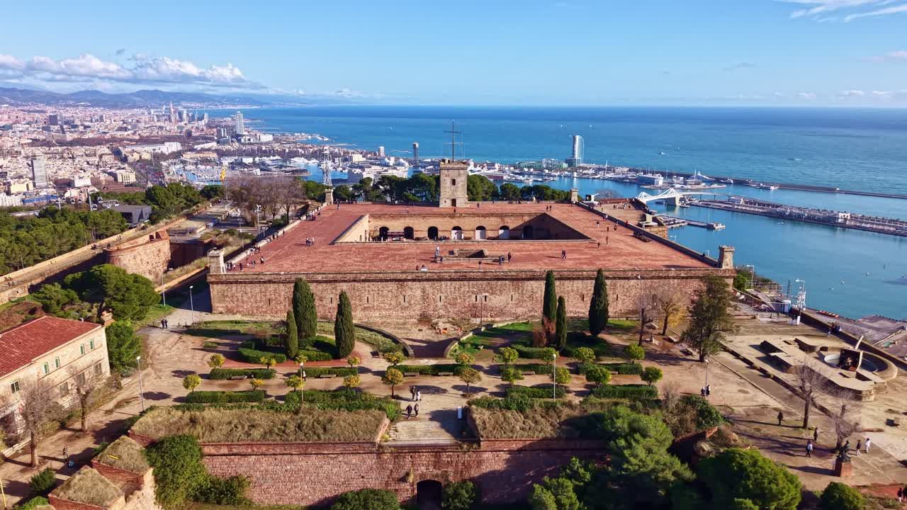 Barselona’ya bakan tarihi taş duvarlara ve kıyı şehir manzarasına sahip Montjuic kalesinin havadan çekimi, sağa doğru takip