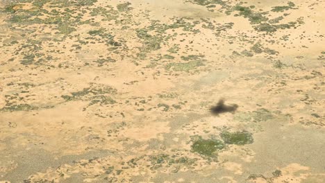 Aerial-view-of-a-plane's-shadow-flying-over-the-dry,-vast,-and-rugged-Australian-outback-landscape