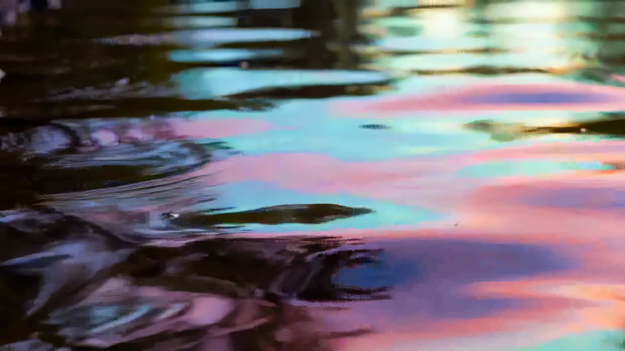 Rippling water surface shifting pastel pink cyan blue reflections on lake from left-edge ripple