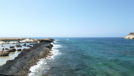 rocky coast of agios georgios beach in cyprus with clear blue waters and sunny skies, wide shot