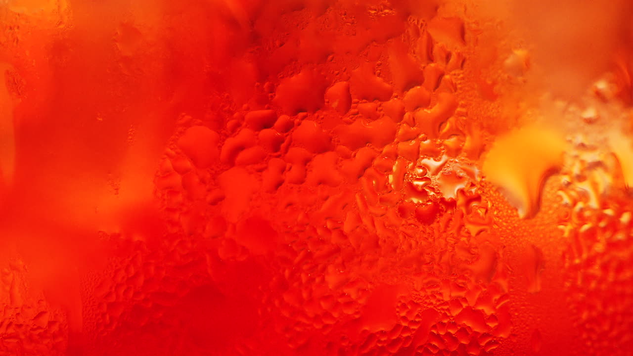 Scatto macro di un cocktail arancione con bollicine e condensa che creano uno sfondo astratto