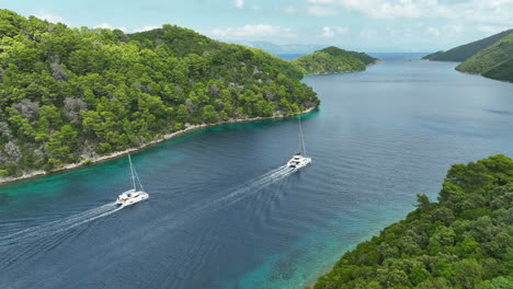 Drone-panning-shot-of-two-catamaran's-sailing-in-a-bay-at-Mljet-Island-on-a-sunny-day