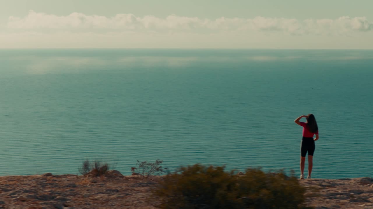 Traveling lateral of a woman watching the mediterranean sea from the top of a mountain