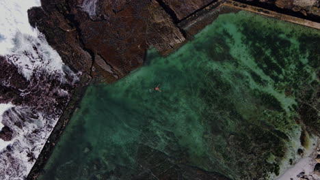 Man-swims-in-rocky-tidal-pool-on-Hermanus-coastline