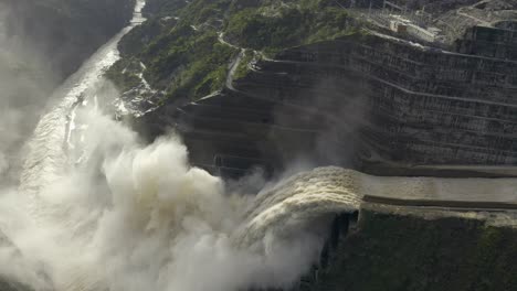 Camera-flies-upriver-from-the-rushing-water-of-the-Cauca-river-to-the-flood-gates-of-the-Hidroituango-dam,-located-in-Ituango,-Antioquia,-Colombia