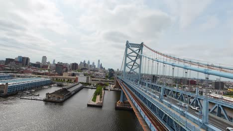 FPV-Flug-Entlang-Der-Benjamin-Franklin-Bridge-Mit-Verkehr-Und-Der-Skyline-Von-Philadelphia-Im-Hintergrund