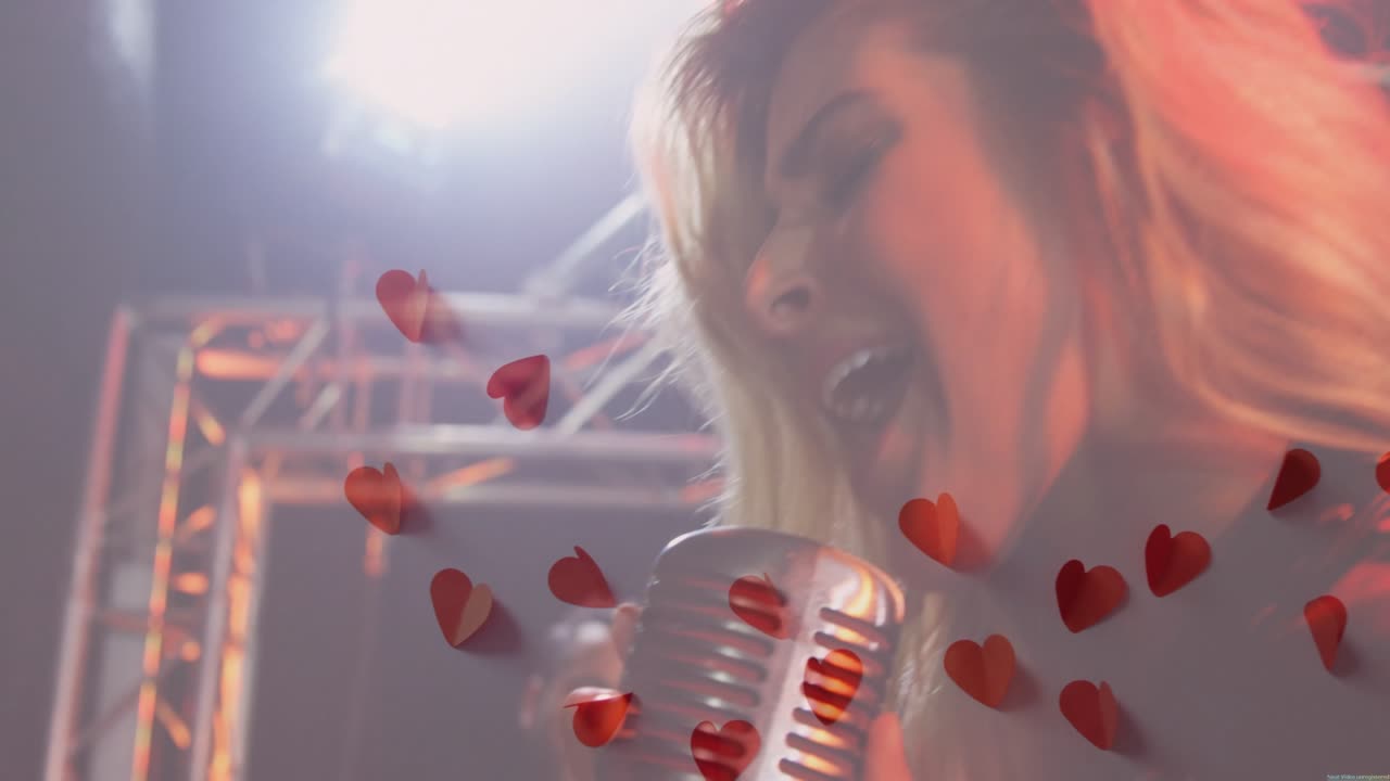 Una cantante si esibisce, la telecamera si allontana rivelando una chitarra mentre cuori fluttuano sull'obiettivo
