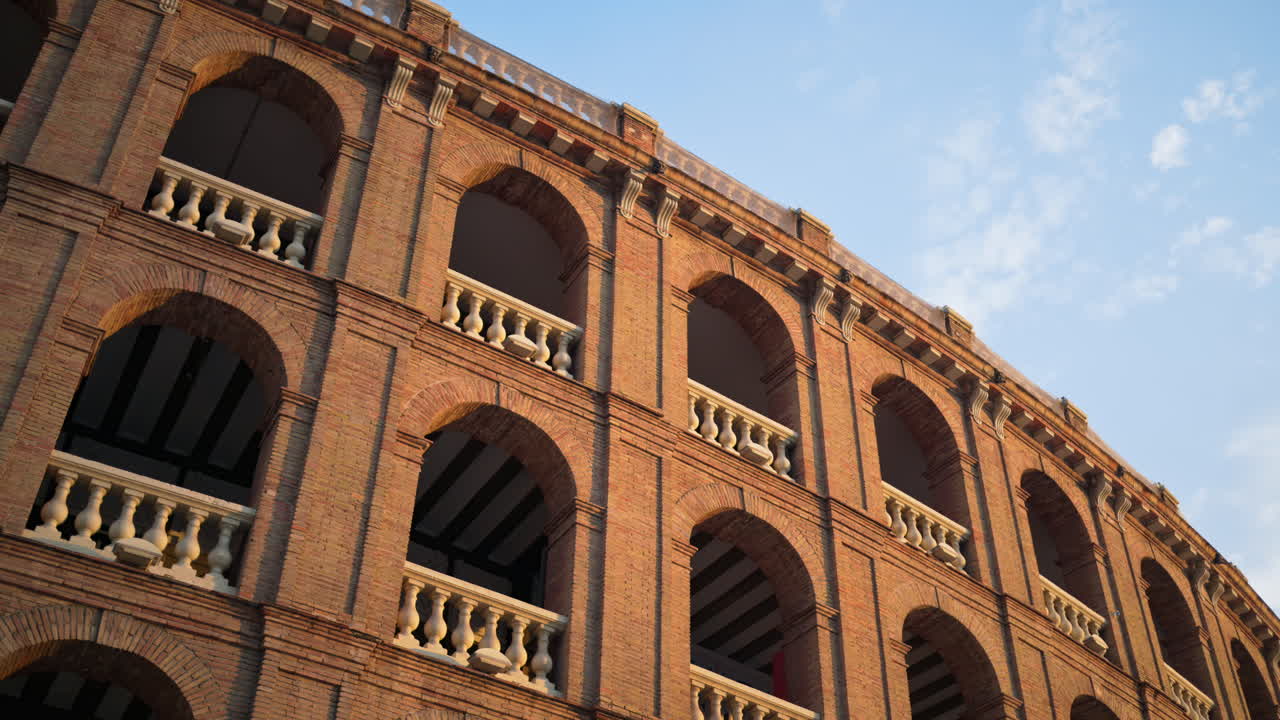 Low angle view of a brick facade with repeated arches and stone balustrades in Valencia, Spain