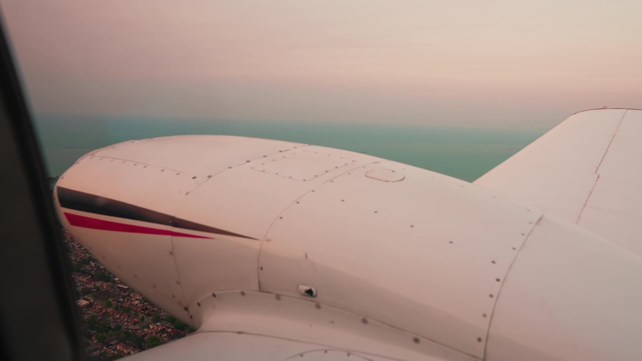Aerea con grana analogica: la navicella di un PA-30 inquadra la costa industriale del sud di Chicago sopra il Lago Michigan color ottanio al tramonto.