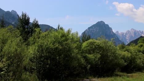 Dreamy-shot-of-Italian-Dolomites-from-the-cycling-path,-looking-through-a-row-of-bright-green-trees