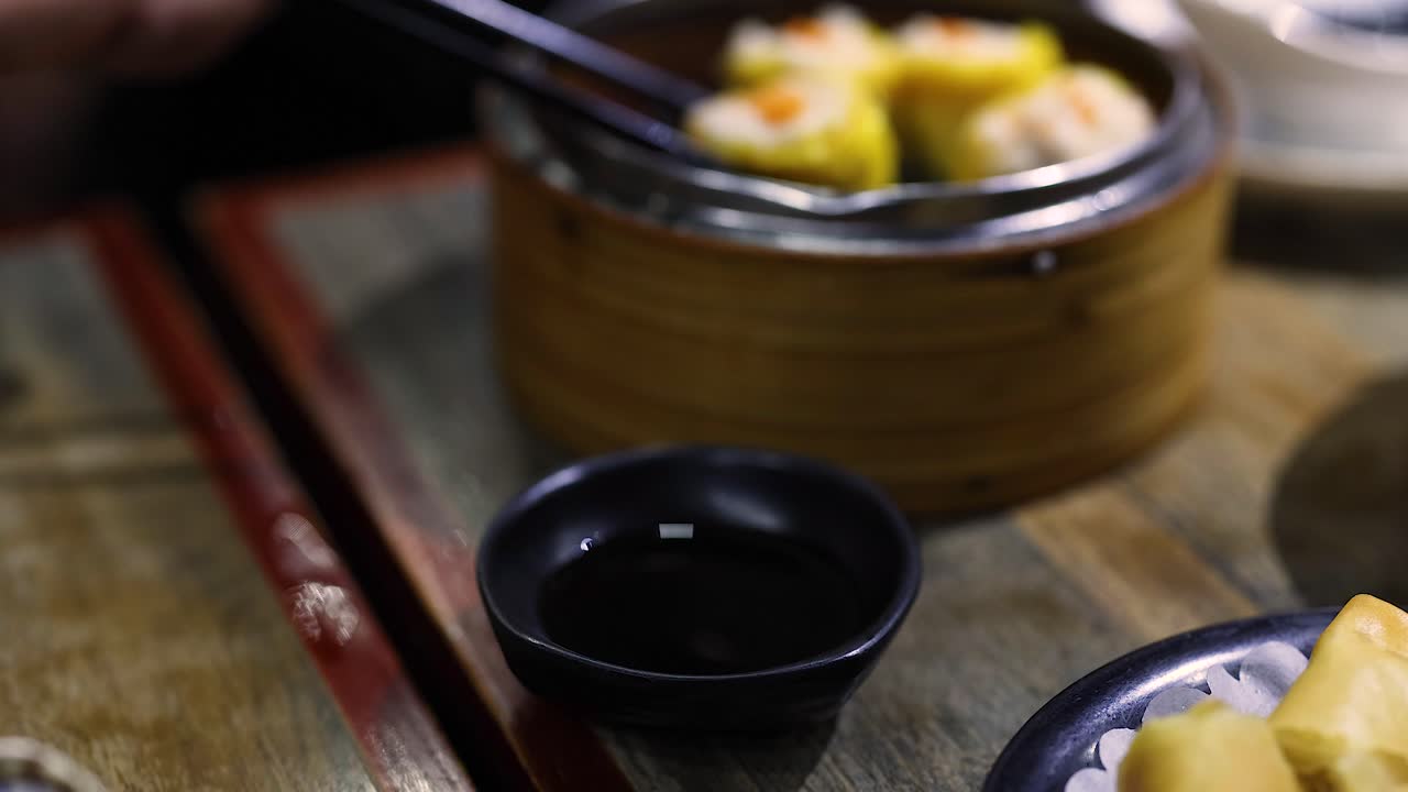 Chopsticks picking dumplings from a bamboo steamer