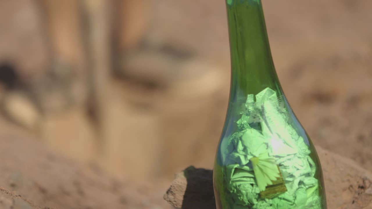 botella verde llena de papeles y hombre cavando un agujero en el fondo
