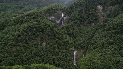 dos grandes cascadas en el bosque en suiza, vuelo aéreo hacia adelante