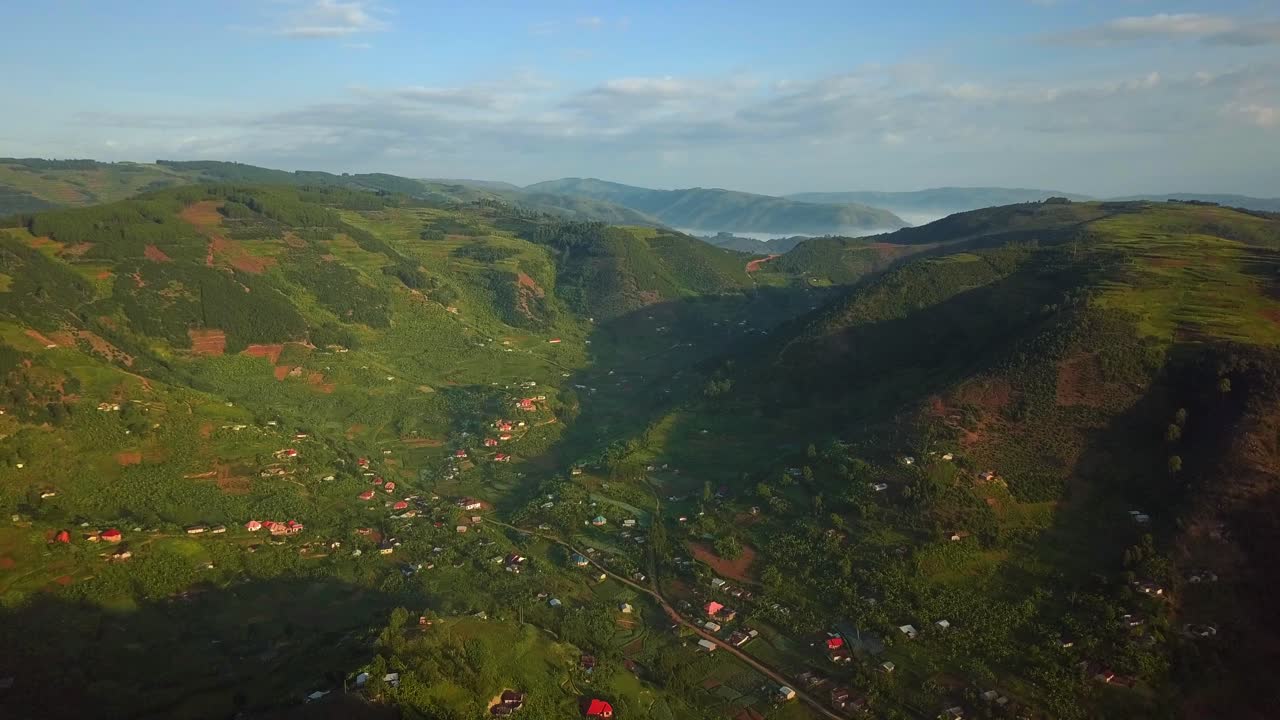 Kabale Uganda green hills and valleys unfold from an aerial perspective, revealing a vibrant rural landscape dotted with small villages and a network of roads, showcasing the rich agricultural land