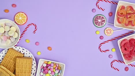 moving sweets, candies and lollipops arrangement on pastel purple background. stop motion flat lay