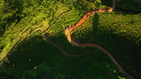 aerial view of winding mountain road through lush green hills