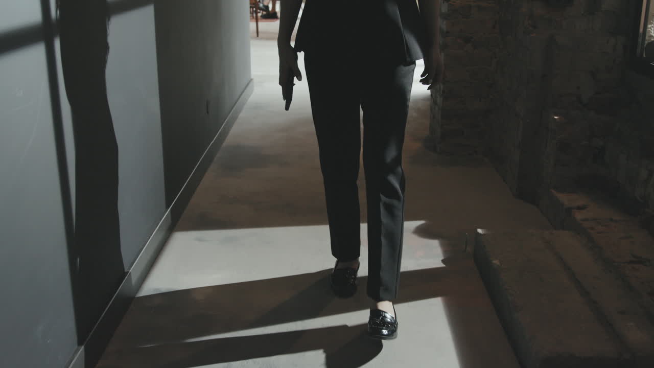 Unrecognizable Business Lady Walking through Dark Office Corridor